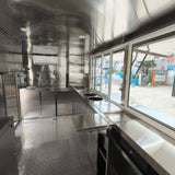 Stainless steel interior of a custom beverage trailer with open service windows, sliding panels, and commercial workspace