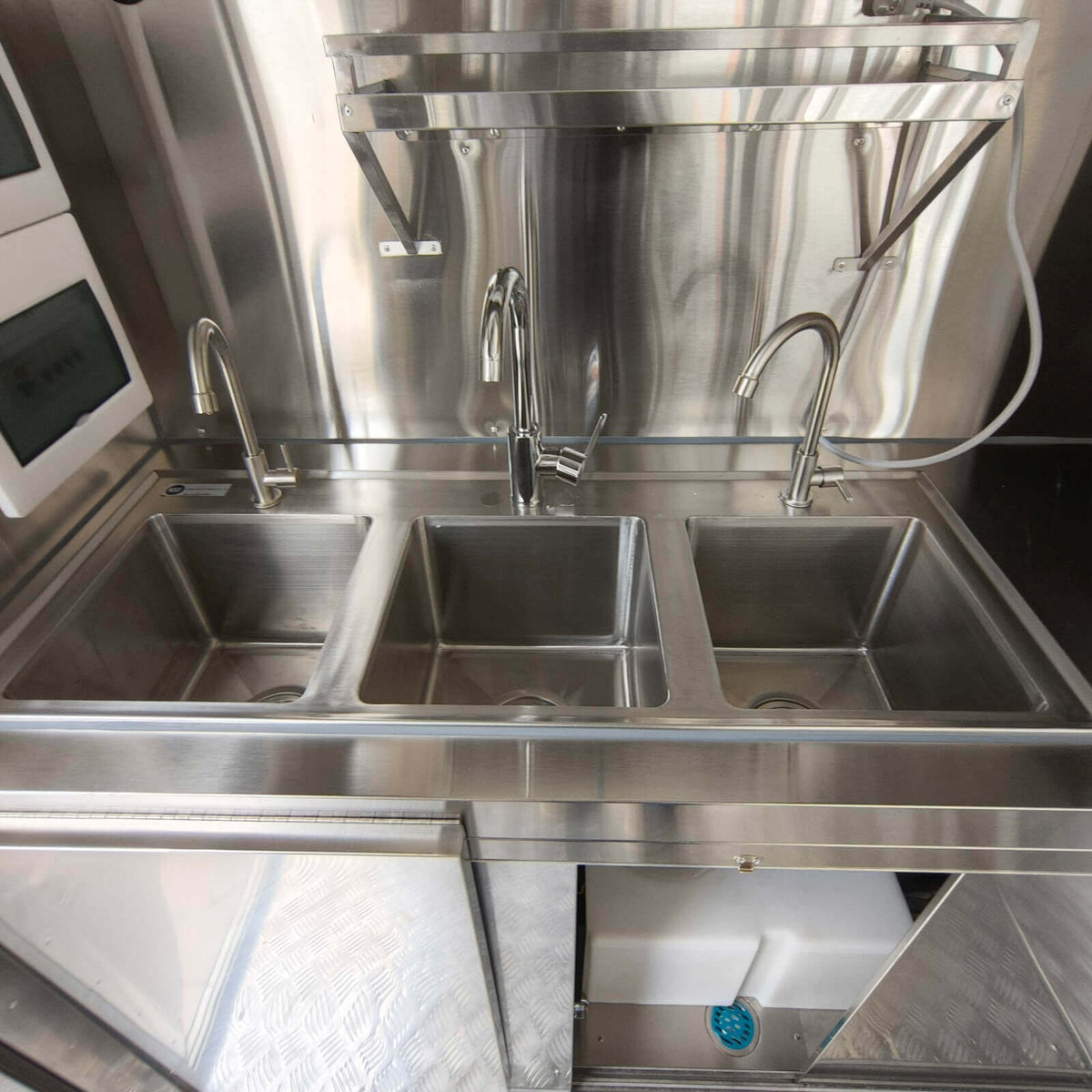 Interior view of a beverage trailer with stainless steel three compartment sink for commercial drink preparation and cleaning