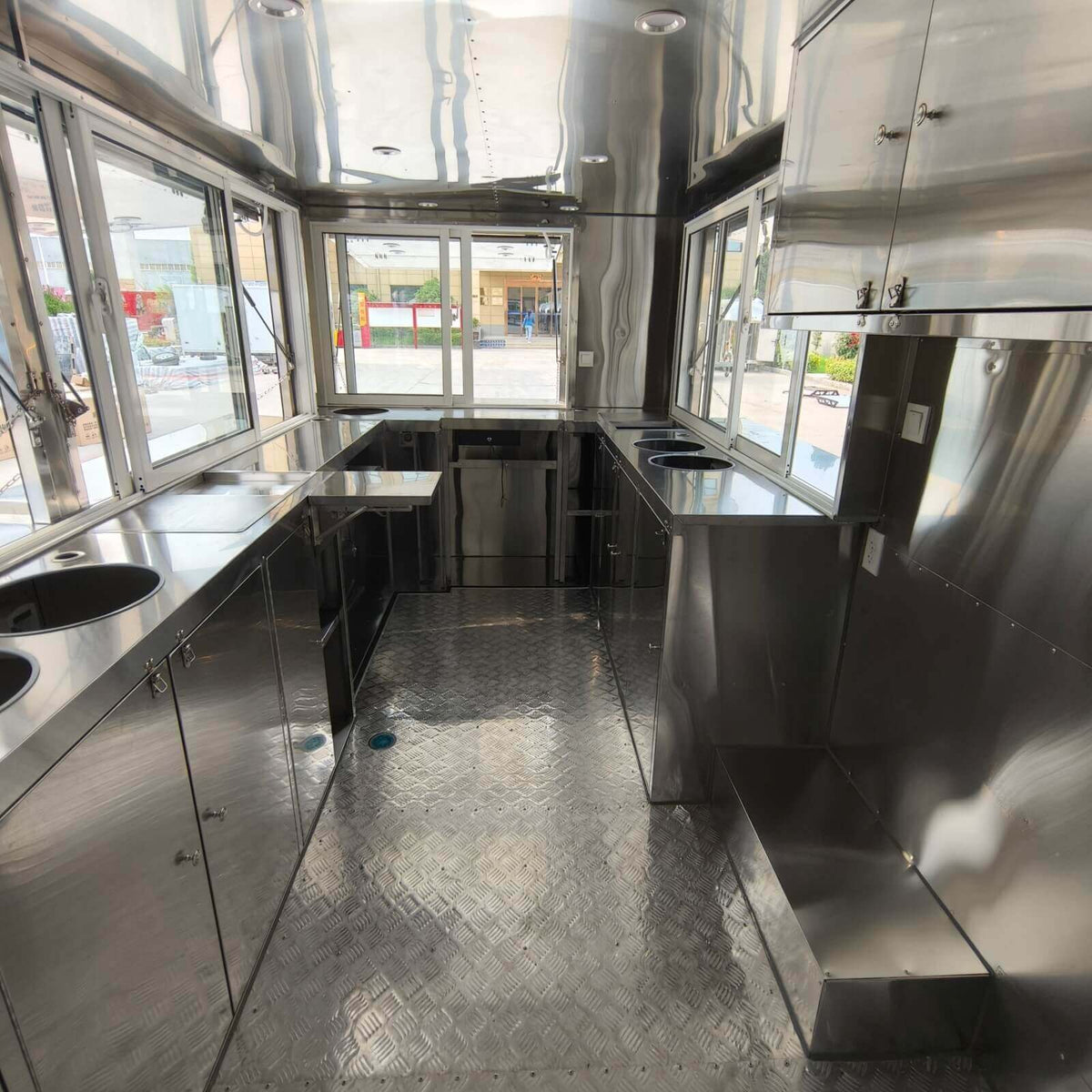 Commercial drink trailer interior featuring multiple service windows, stainless steel counters, sliding windows, and durable flooring
