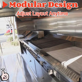Interior view of a commercial food trailer featuring stainless steel walls, a commercial exhaust hood, large grill and griddle equipment, under-counter storage cabinets, and anti-slip flooring.