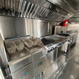 Interior view of a custom kebab food trailer with stainless steel kitchen equipment, flat-top griddle, and commercial exhaust hood system.
