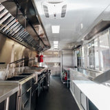 Full kitchen interior of competition BBQ food truck with fire suppression system and serving window