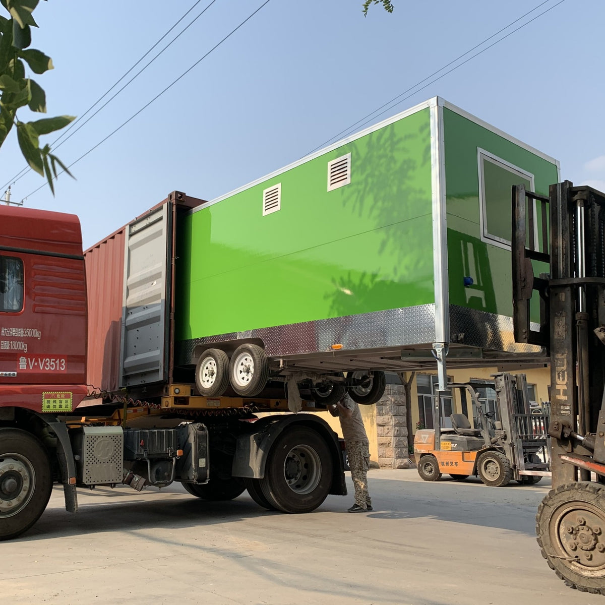 Green concession trailer being loaded onto shipping container by forklift – factory direct export food trailer for sale worldwide