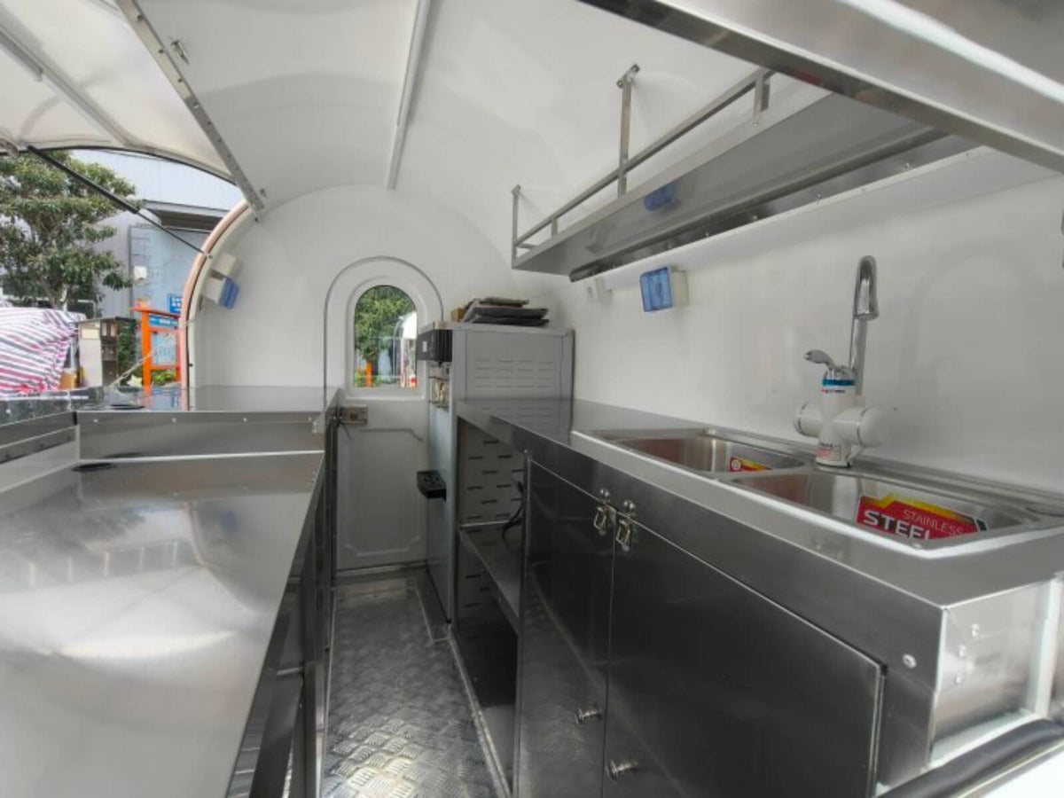 Custom rounded food trailer interior kitchen – stainless steel walls diamond plate floor overhead shelving by Isabella Trailer