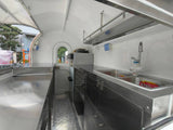 Custom rounded food trailer interior kitchen – stainless steel walls diamond plate floor overhead shelving by Isabella Trailer
