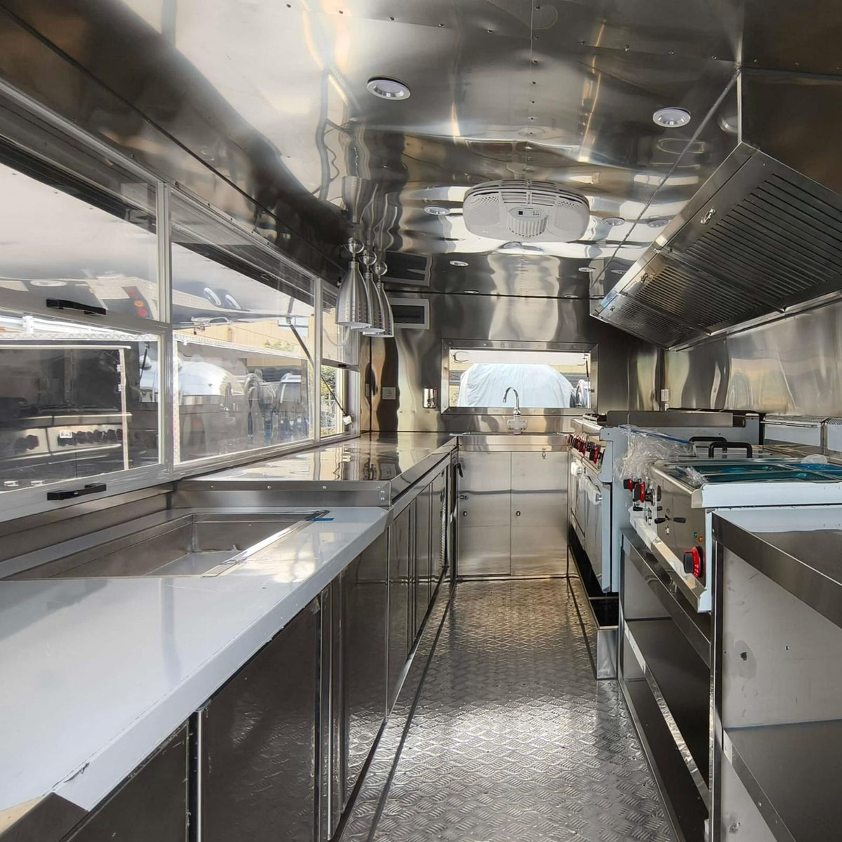 Custom square food trailer interior – full stainless steel commercial kitchen with exhaust hood and prep counters by Isabella Trailer