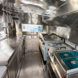Custom square food trailer kitchen interior – stainless steel gas stove, sink, exhaust hood and prep counters by Isabella Trailer
