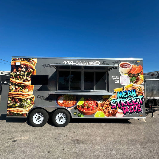 Side exterior view of a custom taco food trailer featuring a full-body graphic vinyl wrap, an open concession service window, and a heavy-duty dual axle chassis.