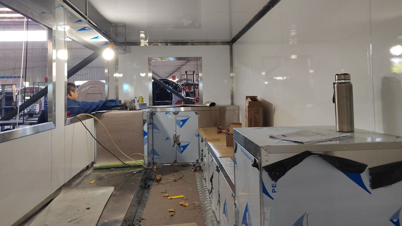 Food trailer interior fit-out in progress with white wall panels and stainless steel counters – Isabella Trailer factory