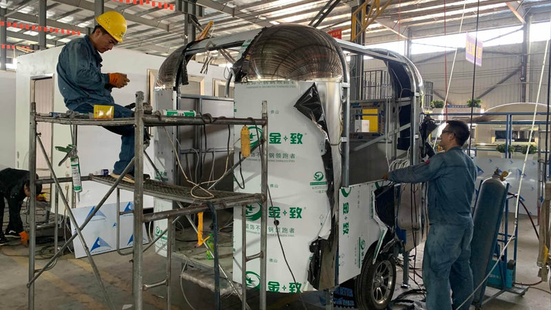Factory workers installing exterior panels on airstream food trailer – Isabella Trailer Zhengzhou China