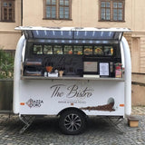 Front service window view of a rounded white coffee trailer with a menu board and commercial espresso machine workspace.