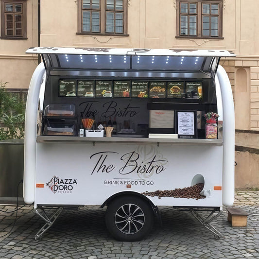 Front service window view of a rounded white coffee trailer with a menu board and commercial espresso machine workspace.