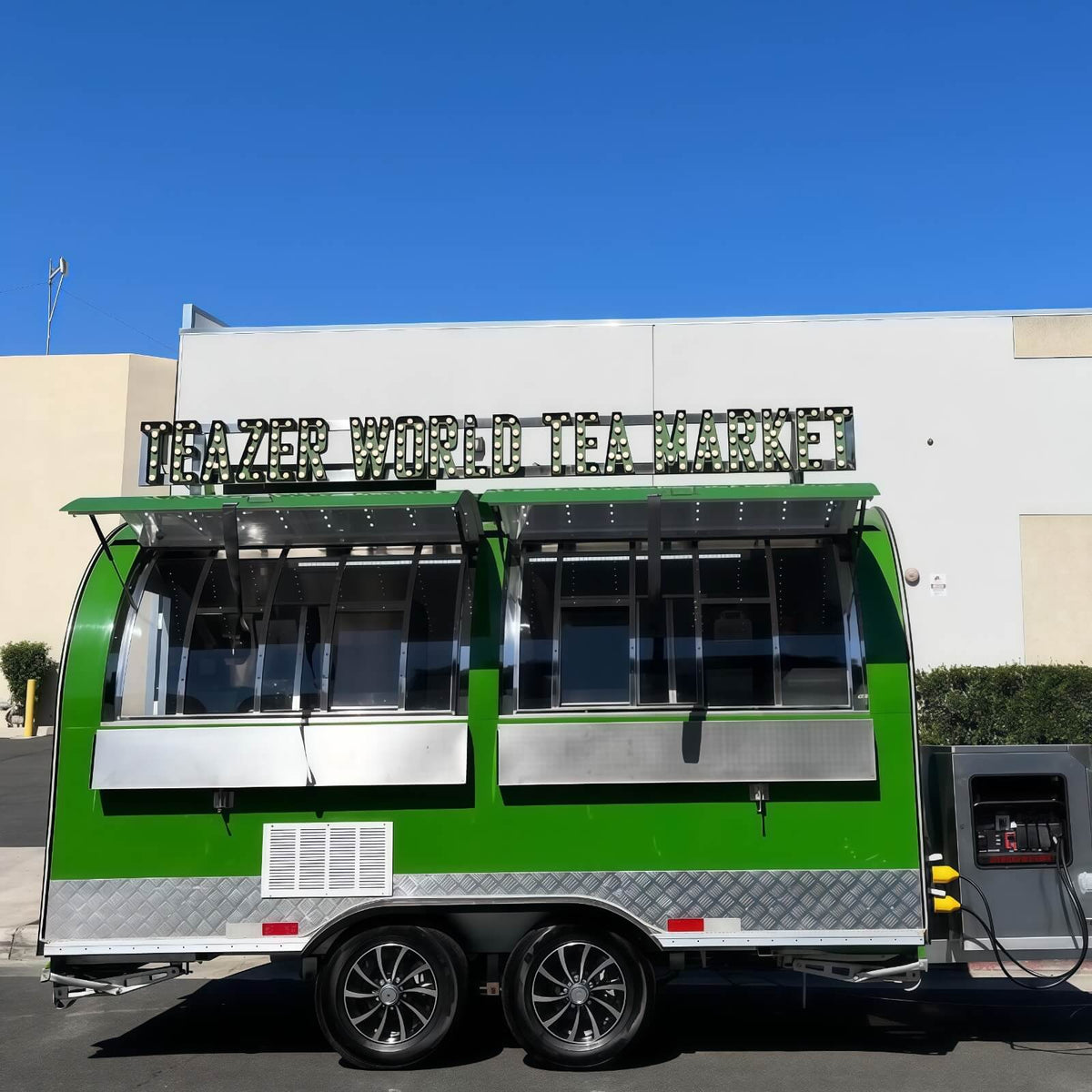 Front view of a green rounded concession trailer featuring an open window with interior star lights and a custom roof LED sign board